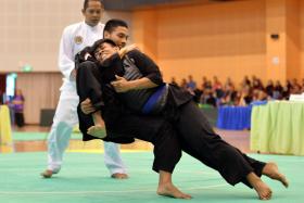 DOWN YOU GO: Seni Grasio’s Alfian Juma’en executing a takedown on his opponent (with blue sash) at the National Championships at Pasir Ris Sports Hall yesterday. 