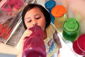 FEELING THE HEAT: Five-year-old Aisyah Zahra drinking cold water ﻿to ﻿while standing in front of the ﻿refrigerator﻿.