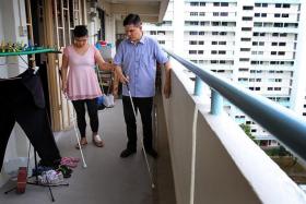 FOLLOW ME: Mr Suhaime Roa teaching Madam Siti Hajar Abdul Gaffar how to navigate the corridor outside her flat with a walking cane.