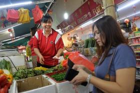 FAMOUS: Everyone at Jurong West knows vegetable seller Beh Poh Gek (in red shirt) for her friendliness and loud voice.