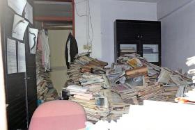CLUTTER: Stacks of yellowed newspapers fill the living room, leaving little space to move around.
