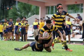 VALIANT ATTEMPT: ACS (I)&#039;s two-try scorer Edward Hui (holding ball) being tackled by an ACJC player en route to their 45-5 win yesterday.