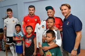 STARS PAY VISIT: Valencia striker Santi Mina (left), goalkeeper Mathew Ryan (second from left) and former midfielder Gaizka Mendieta (right) visit a family at their home at Beo Crescent.