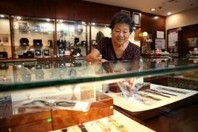PASSIONATE: Madam Helen Tan painstakingly writes down the details and condition of every second-hand watch put up for sale.