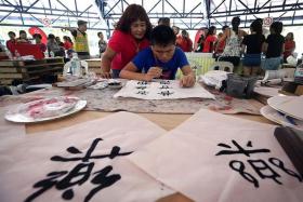 FOCUSED: (Above) Leow Wei En, 18, was introduced to calligraphy just seven months ago. At the Rock Our Blocks party, he demonstrated his skill with confidence. His mother Jocelyn Toh, 52, watches as he practised his craft.