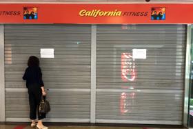 A member peering through the shutters of the now-closed California Fitness&#039; Novena Square outlet on the afternoon of July 20. 