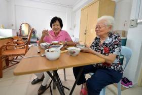 TOGETHER: (From left) Madam Hou Wah Cheng and Madam Lee Ah Sim, both 80, share a meal in their one-room rental flat at Pipit Road.