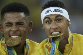  Neymar (right) and Gabriel Jesus of Brazil bite their medals.