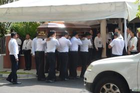 PAYING RESPECTS: (Above) Pallbearers carrying Mr S R Nathan&#039;s casket into his family home. 