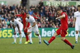 HE&#039;S THE MAN:  James Milner (in red) converting the penalty for the Reds&#039; winner.
