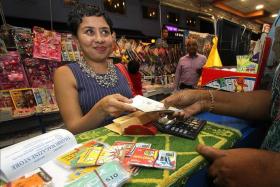 PHONE HOME: Ms Dipa Swaminathan buying phone cards to distribute to migrant workers during Deepavali.
