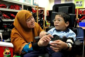 Madam Faridah Thamby calming her son, Fahmi, down by gently touching his arm and singing to him. 