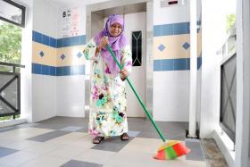 Madam Zulaika sweeping away rainwater that had collected along the common corridor.