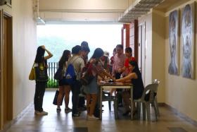 Affected Hwa Chong Institution students registering to enter a room for a briefing on their stolen papers.