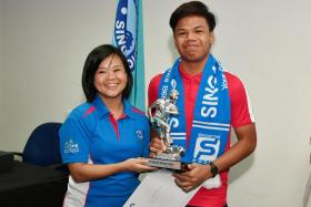 Singapore Pools' assistant manager for community partnerships, Tay Siow Chien, handing the TNP Dollah Kassim Award trophy to the 2018 winner Nur Adam Abdullah, who will get an overseas training stint, courtesy of Pools.