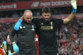 Liverpool goalkeeper Alisson (right) receiving medical treatment for a calf injury.