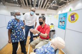 Mr Chan Chun Sing (in red) and Mr Janil Puthucheary (in white) during a tour of the vaccination centre at Senja-Cashew Community Club on Dec 26, 2021.