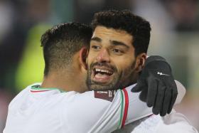 Iran's forward Mehdi Taremi (right) celebrates his goal with a teammate.
