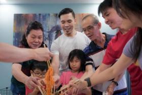 Mr Png Zhijie (white top) with his family tossing yusheng during a reunion dinner on Jan 30, 2022.