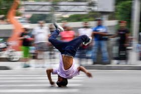 Kenyer Mendez, who dreams of joining Venezuela's breakdance team for the 2024 Olympics, performing a head slide at a traffic light in Caracas.