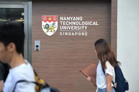 Students walking past a Nanyang Technological University (NTU) logo at the school&#039;s global lounge. 