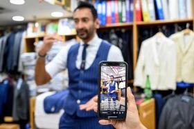 Roshan Melwani of Sam&#039;s Tailors is filmed by his team as he talks to a client in the US at his shop in Hong Kong. 