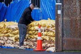A man stacks up sandbags to protect a warehouse before the arrival of Cyclone Gabriele in Auckland, New Zealand, on Feb 12, 2023. 