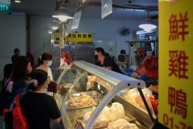 Customers buying fresh chicken from a poultry stall in Tiong Bahru market on May 31, 2022.
