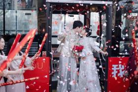 Newly-weds Ma Yuxuan and Cai Yang posing for a photo on a wedding bus in Qingdao, East China’s Shandong province, on Dec 9, 2023. 
