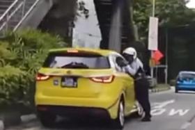 In a YouTube video, a traffic police officer can be seen with his hand trapped in the window of a yellow taxi parked at the side of the road.