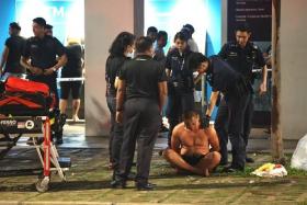 The man was seen handcuffed and sitting cross-legged by the road surrounded by police officers before being led into a police car.