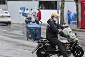A delivery man rides a scooter to deliver an order in Shanghai on March 17, 2022.