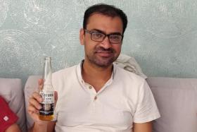 Mr Kovid Kapoor poses for a picture while drinking a Corona beer at a relative&#039;s home in Mumbai.