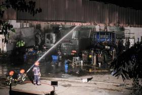 SCDF personnel extinguishing the fire at Yong Sing Motor Works, on Nov 25, 2022.