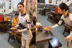 The proprietor, who gave her name only as Ms Qin, can be seen greeting customers, serving dishes, pouring tea and making toasts ‘mechanically’.