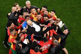 Morocco&#039;s coach Walid Regragui is thrown in the air by his team after winning their quarter-final match 1-0 against Portugal.